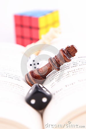 CHESS PIECE WITH DICE ON A BOOK AND RUBIK’S CUBE