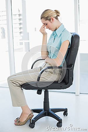Chic businesswoman sitting exhausted on her swivel chair