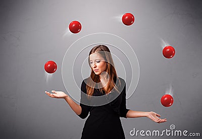 Chica joven que se coloca y que hace juegos malabares con las bolas rojas