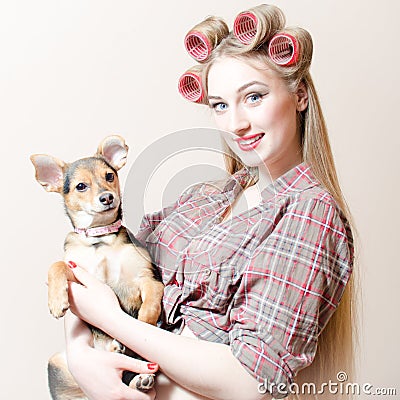Chick & puppy: beautiful sexy blond pinup girl with red lips & curlers in her hair holding a small cute dog happy smiling