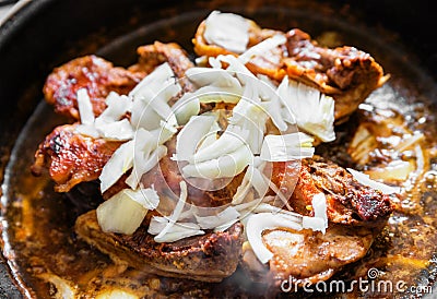 Chicken with onion on frying pan