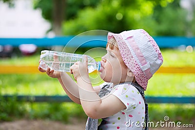 Child drinks from bottle in park