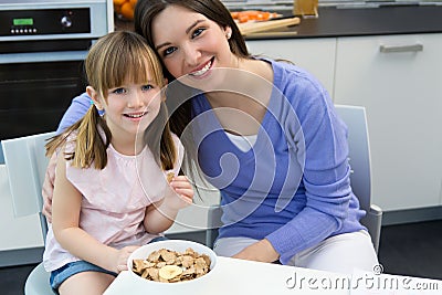 Child eating cereals with her mom in the kitchen