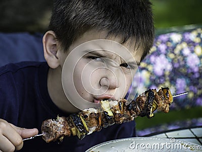 Child eating meat on a skewer