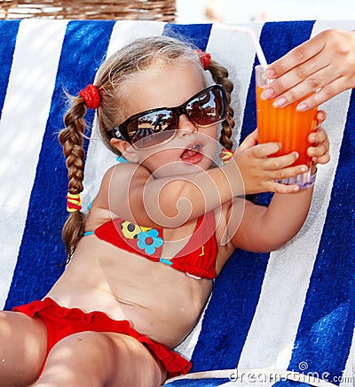 Child girl in red bikini drink juice.