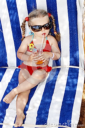 Child in glasses and red bikini drink juice.