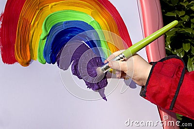 Child painting rainbow on easel in garden