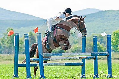 Child-rider with horse jumps over a hurdle