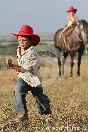 Children in cowboy hat riding horse outdoors