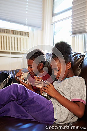 Children With Poor Diet Eating Meal On Sofa At Home