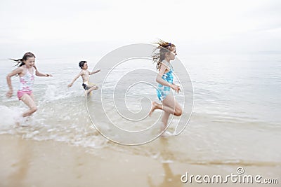 Children Running In Surf At Beach