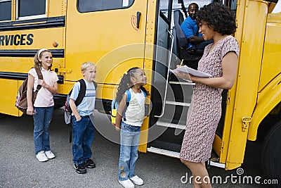Children Standing In A Line By School Bus