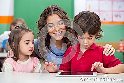 Children Using Digital Tablet With Teacher