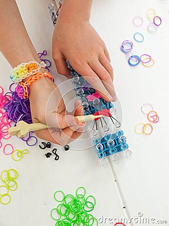 Childs hands with band loom, croche hook and multicoloured elast