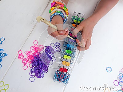 Childs hands with loom and multicoloured elastic bands