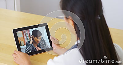 Chinese doctor talking with young woman patient on tablet