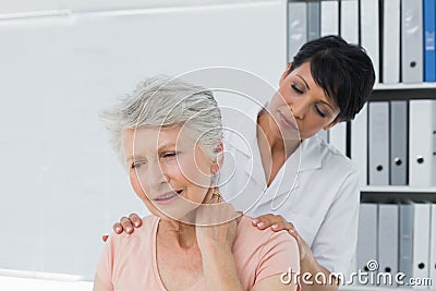 Chiropractor looking at senior woman with neck pain