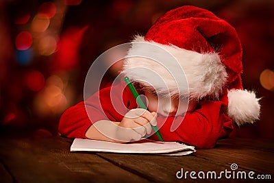 Christmas child writing letter in red Santa hat