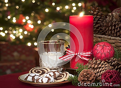 Christmas Cookies and Milk Waiting for Santa Claus in Candle Light with a Lighted Christmas Tree in background on Christmas Eve