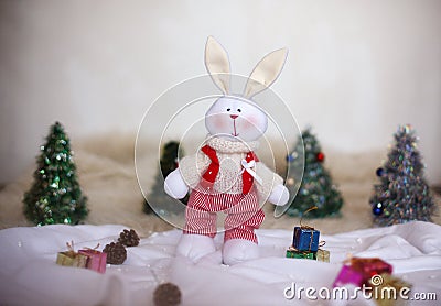Christmas toy rabbit on background trees