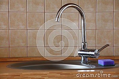 Chrome water faucet in a wooden kitchen