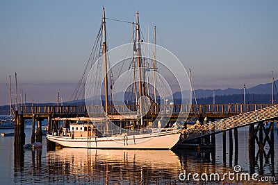 Large classic two mast gaff rigged wooden schooner sailboat docked in 