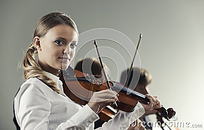 Musicians in concert, beautiful female violinist on foreground.