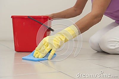 Cleaning floor tiles with sponge and glove.