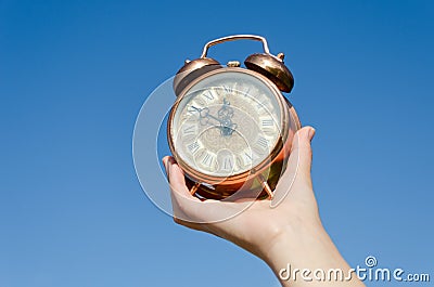 Clock roman numeral in hand on blue sky background
