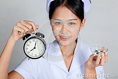 Close up Asian young nurse with clock and pills