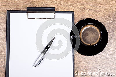Close up of blank clipboard, pen and cup of black coffee on wood