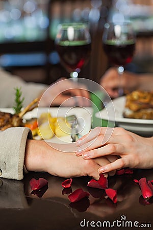 Close up on couple holding hands during dinner