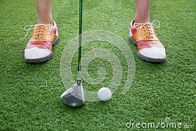 Close up on feet and golf club getting ready to hit a golf ball