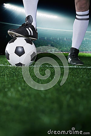 Close up of feet on top of soccer ball, night time in the stadium