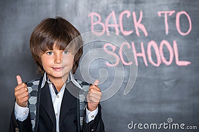 Close-up of little school boy with thumbs up near