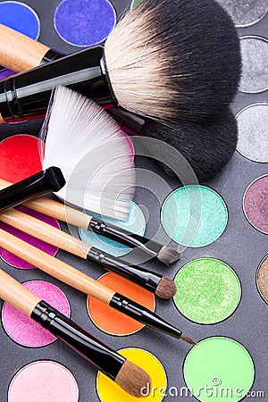Close up of make-up brushes and colorful eyeshadow palette over