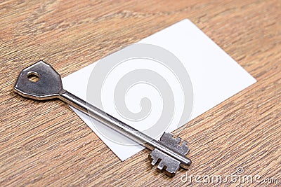 Close up of metal key and visiting card on wooden table