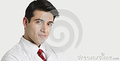Close-up portrait of a handsome Indian male doctor smiling over light gray background