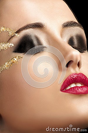 Close-up shot of female face with golden shining eye makeup