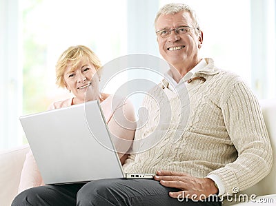 Close up of a smiling senior happy couple in front of a laptop