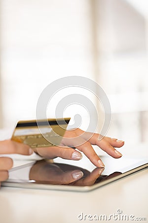 Close-up woman s hands holding a credit card and using tablet pc