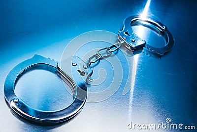 Closed handcuffs on a metallic background with dramatic lighting