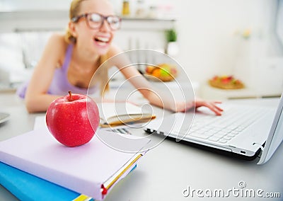 Closeup on apple and smiling woman studying in background