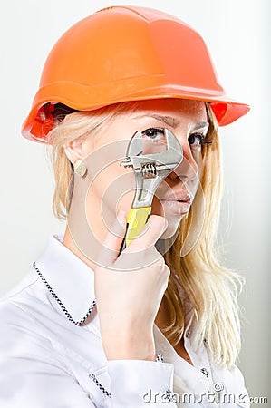 Closeup of blonde woman with builder helmet & adjustable spanner