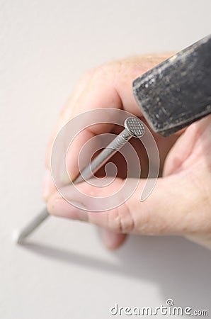 Closeup hand with nail and hammer at wall