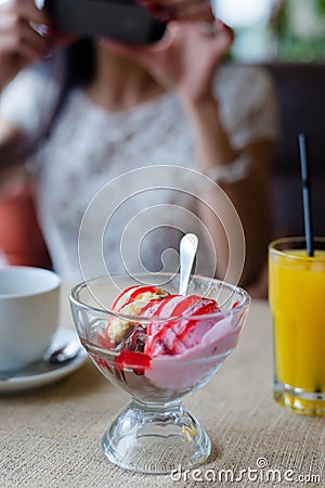 Closeup on ice cream in restaurant with female girl having fun holding mobile device taking selfie photo