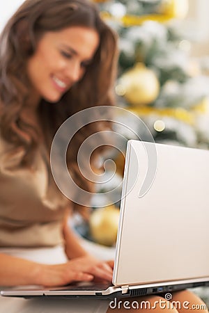 Closeup on laptop used by young woman near christmas tree