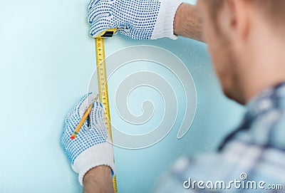 Closeup of male in gloves measuring wall with tape