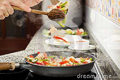 Closeup of man cooking vegetables and chicken in a pan