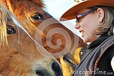 Closeup young pretty woman talking to two horses